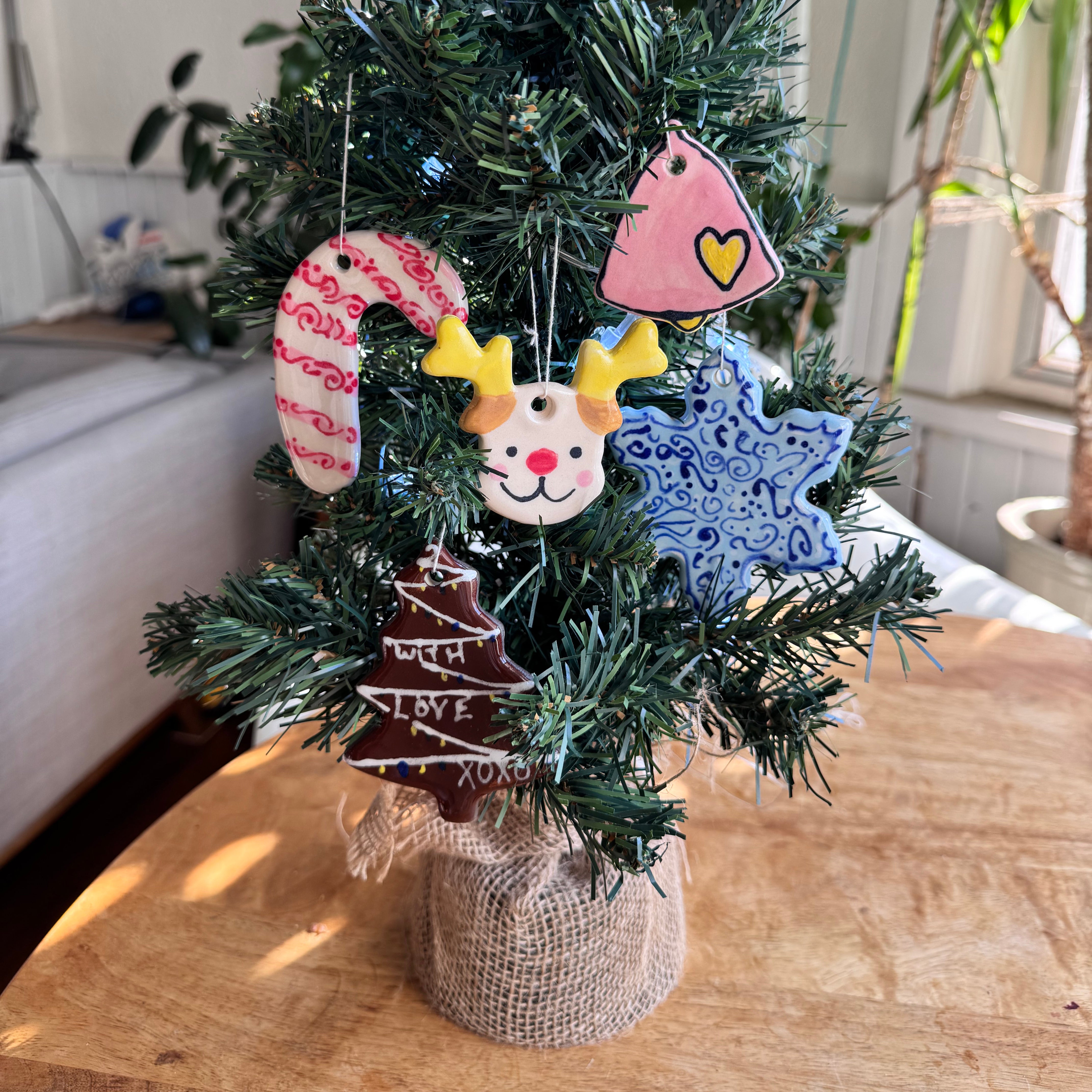 A miniature christmas tree decorated with hand painted ceramic ornaments 